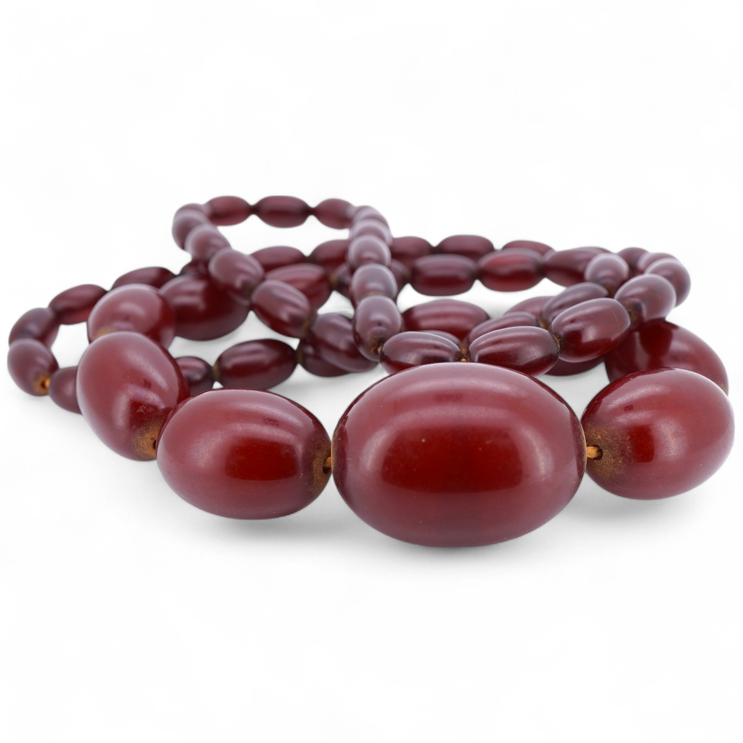 A cherry-coloured bakelite 'amber' necklace, composed of graduated oval beads measuring approximately 1.1-3cm, length 76cm, gross weight 66 grams, Condition: good, minor wear